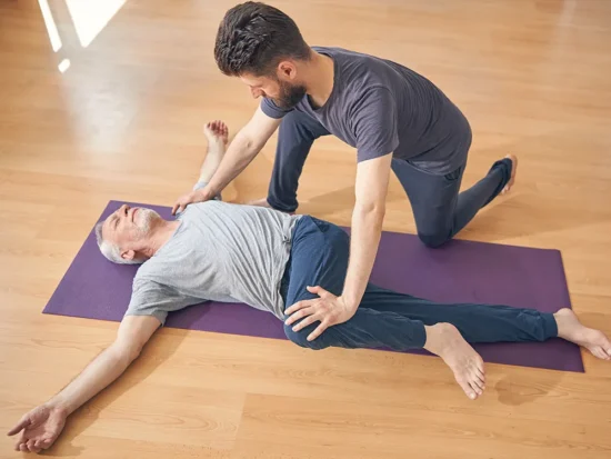 Man Receiving Assisted Stretch on Mat in Studio